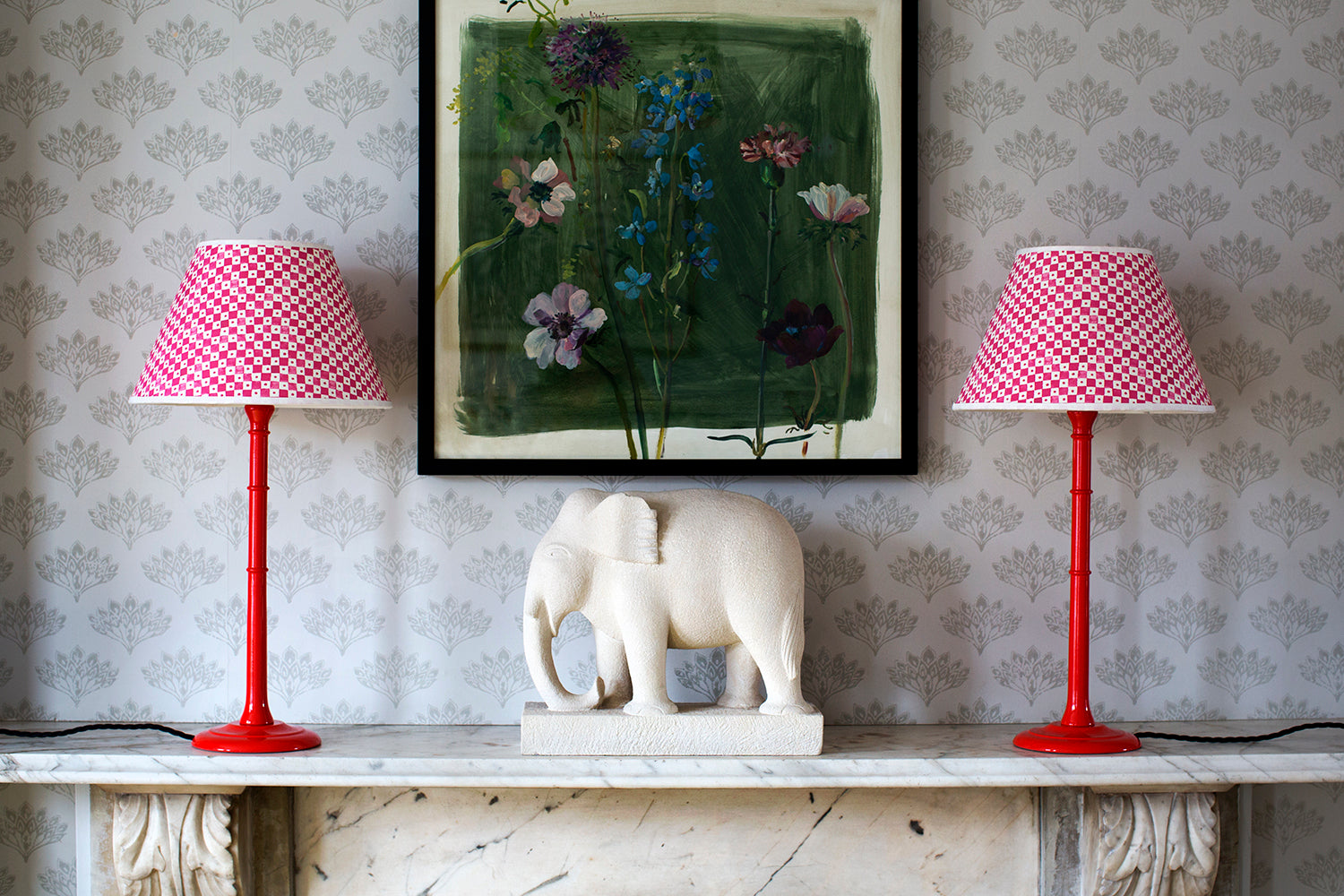 Geometric handmade paper lampshades and red glossy lamps on a mantlepiece 